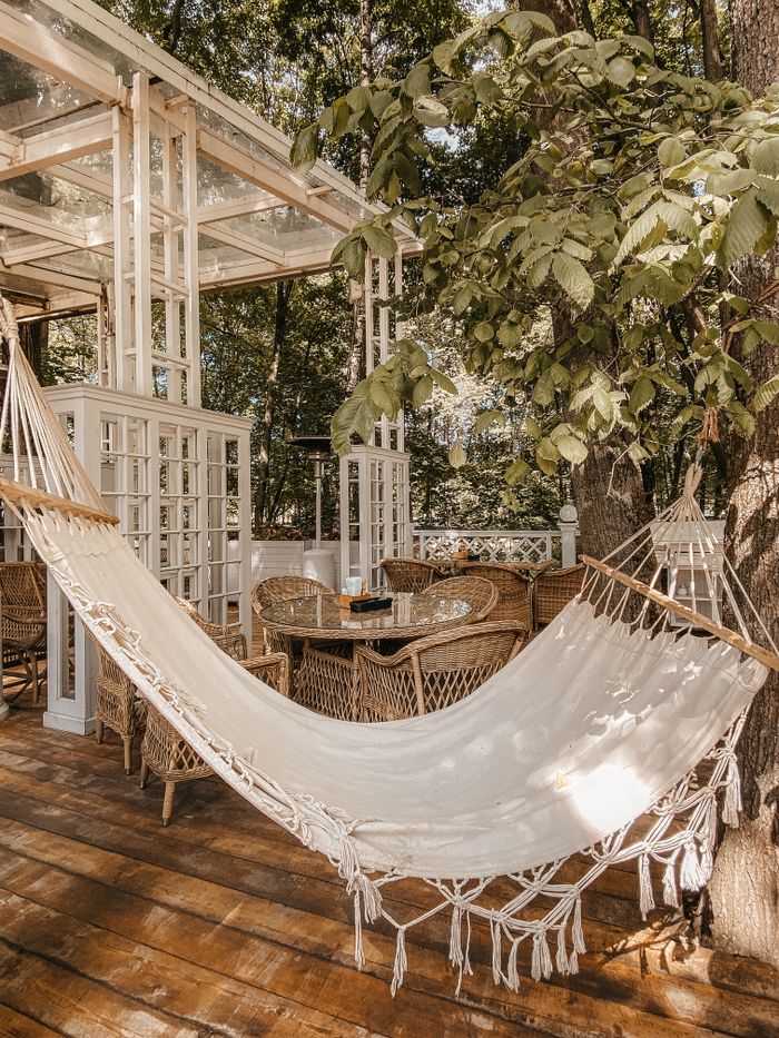 Relaxing scene with a hammock under trees on a cozy wooden deck patio.